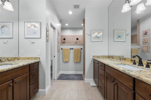 bathroom featuring tile patterned flooring, toilet, vanity, and tiled shower