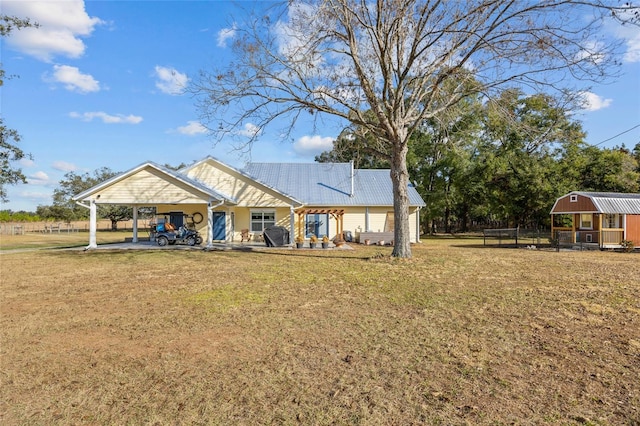 rear view of property with a lawn, an outbuilding, and a carport