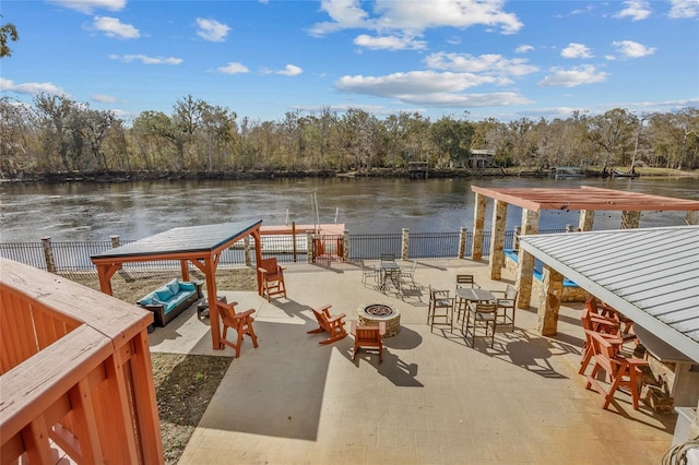 view of dock with a water view, an outdoor fire pit, and a patio area