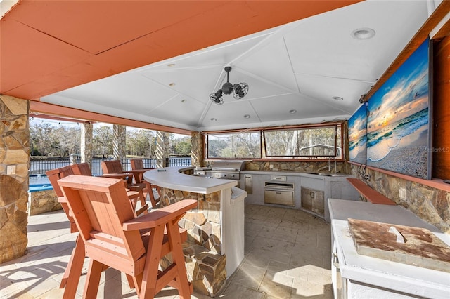 view of patio with a gazebo, a wet bar, area for grilling, and exterior kitchen