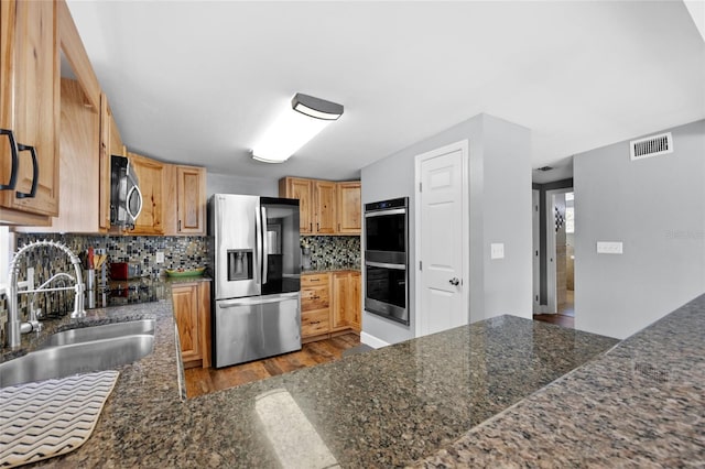 kitchen with tasteful backsplash, sink, stainless steel appliances, and light hardwood / wood-style floors