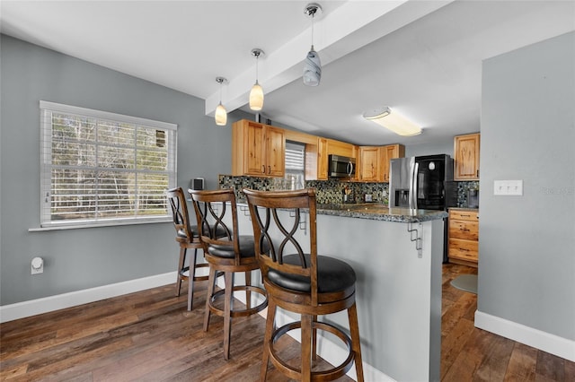 kitchen with pendant lighting, a kitchen breakfast bar, decorative backsplash, appliances with stainless steel finishes, and kitchen peninsula