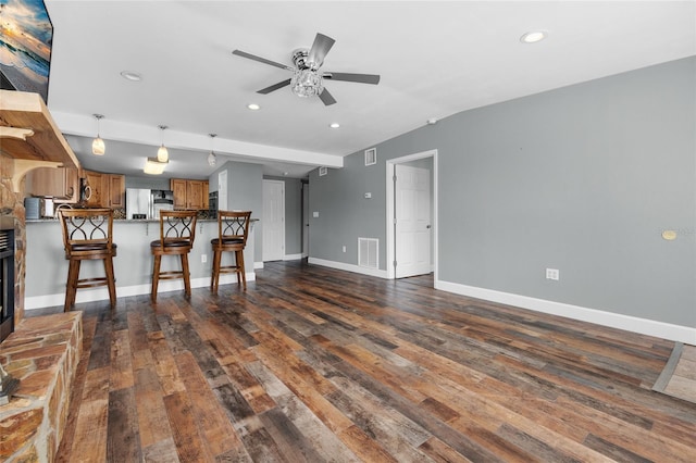 unfurnished living room featuring a stone fireplace, ceiling fan, and dark hardwood / wood-style flooring