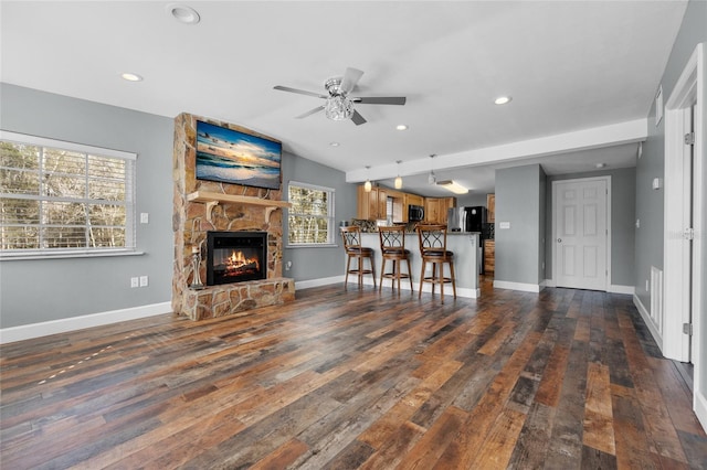 unfurnished living room with a fireplace, lofted ceiling, ceiling fan, and dark wood-type flooring