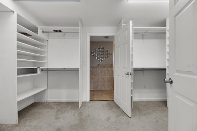 walk in closet featuring light colored carpet