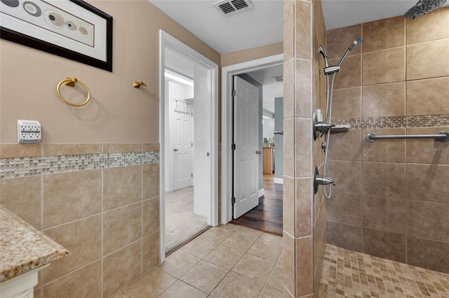 bathroom with tile patterned flooring and a tile shower