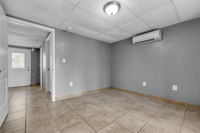 tiled empty room featuring a wall unit AC and a drop ceiling