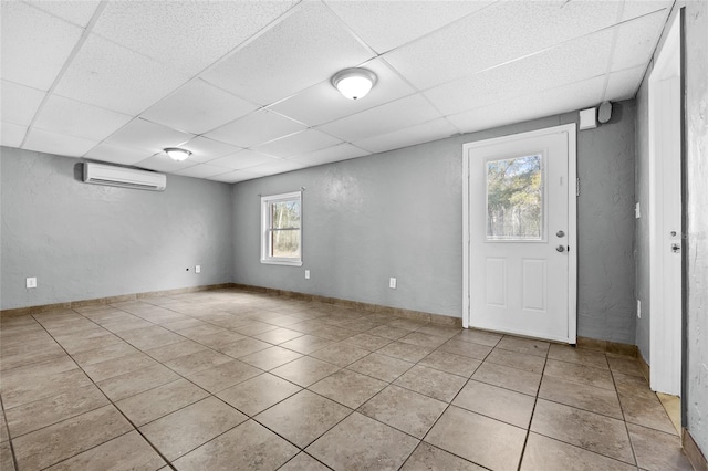 interior space with an AC wall unit, a drop ceiling, and plenty of natural light