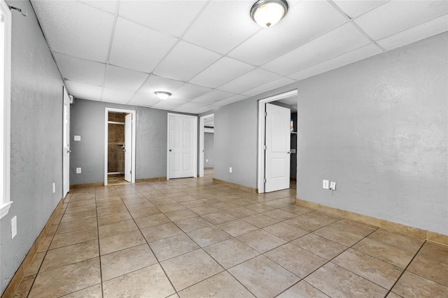 unfurnished room with light tile patterned floors and a drop ceiling