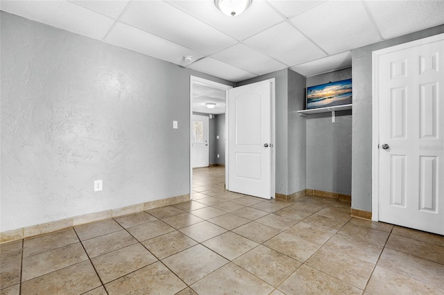 unfurnished bedroom with a paneled ceiling, a closet, and light tile patterned floors