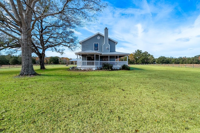 rear view of property with covered porch and a lawn