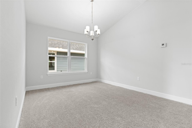 carpeted empty room with an inviting chandelier and lofted ceiling