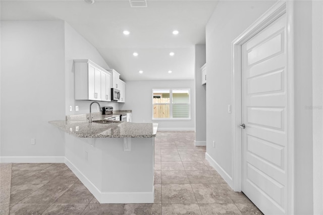 kitchen featuring light stone countertops, sink, kitchen peninsula, white cabinets, and appliances with stainless steel finishes