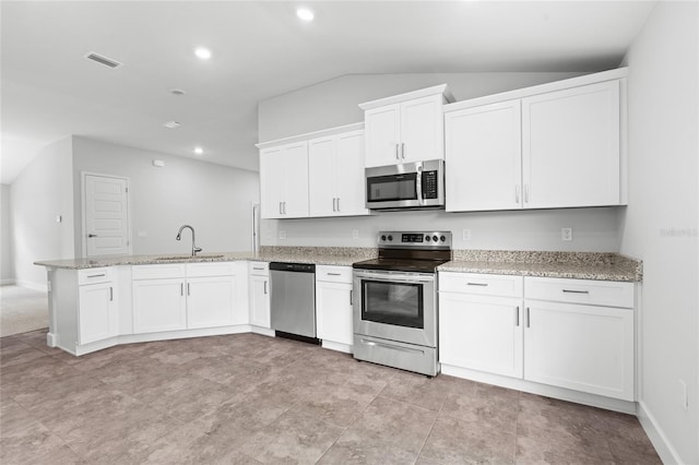 kitchen with light stone countertops, stainless steel appliances, sink, white cabinetry, and lofted ceiling