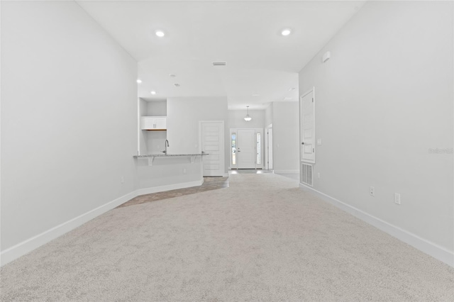 unfurnished living room with sink and carpet floors