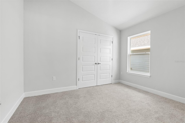 unfurnished bedroom with a closet, carpet floors, and lofted ceiling