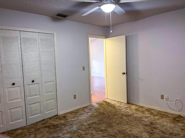 unfurnished bedroom featuring carpet flooring, a textured ceiling, a closet, and ceiling fan