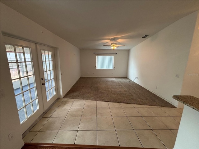 empty room with ceiling fan, light colored carpet, and french doors