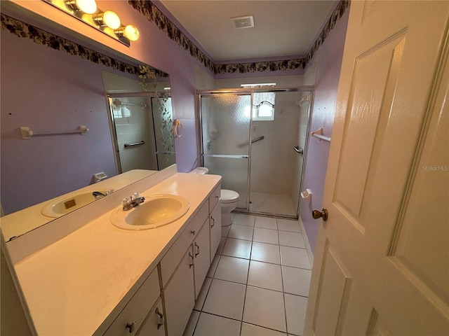 bathroom with toilet, vanity, tile patterned floors, and a shower with shower door