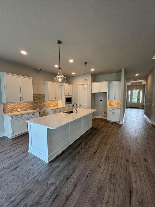 804 SW 144th Dr, Newberry, FL 32669 - kitchen featuring built in microwave, white cabinetry, dark wood finished floors, a spacious island, and tasteful backsplash