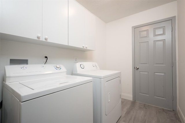 laundry area with independent washer and dryer, cabinets, and light hardwood / wood-style flooring