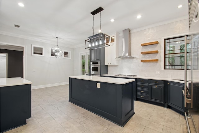 kitchen with a kitchen island, hanging light fixtures, wall chimney range hood, and appliances with stainless steel finishes