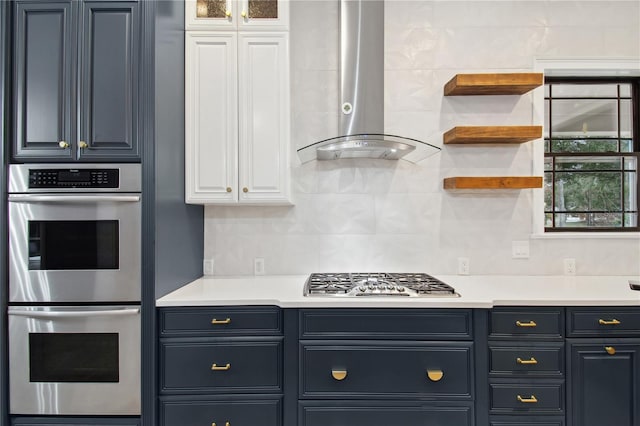 kitchen with wall chimney exhaust hood, decorative backsplash, white cabinets, and stainless steel appliances