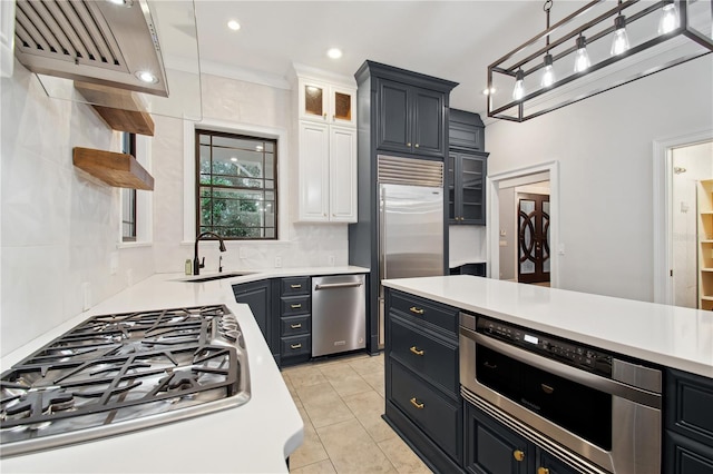 kitchen featuring backsplash, hanging light fixtures, sink, appliances with stainless steel finishes, and white cabinetry