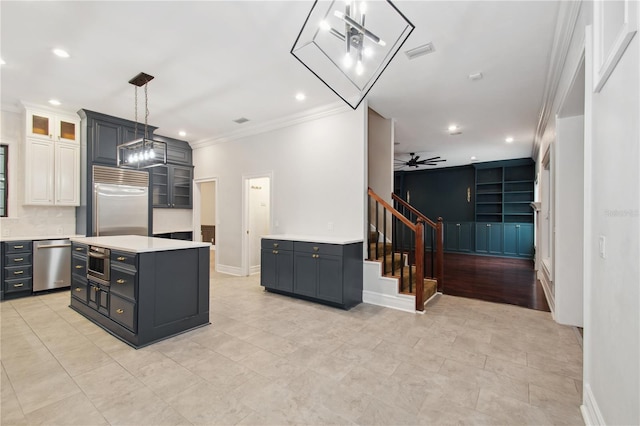 kitchen with stainless steel appliances, ceiling fan, white cabinets, a center island, and hanging light fixtures