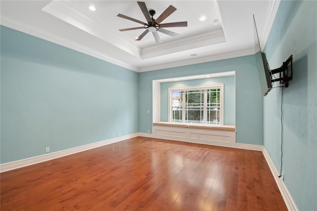 unfurnished room with hardwood / wood-style floors, ceiling fan, a raised ceiling, and ornamental molding