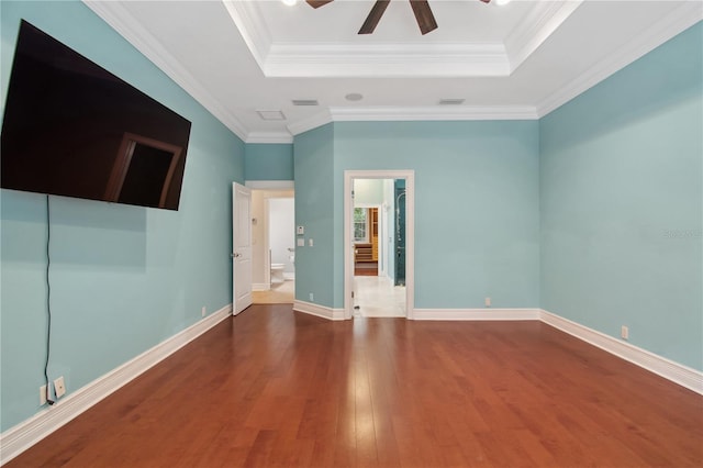 unfurnished room featuring a tray ceiling, crown molding, dark hardwood / wood-style flooring, and ceiling fan