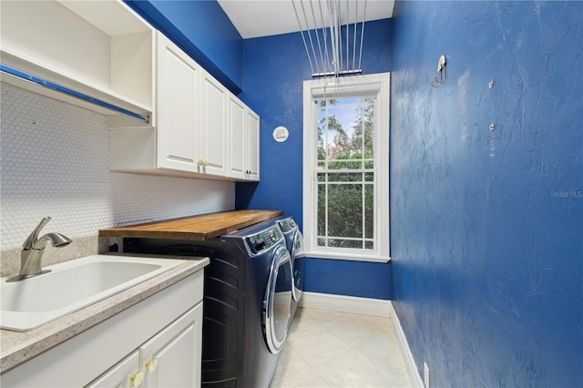 laundry area featuring cabinets, separate washer and dryer, sink, and light tile patterned floors