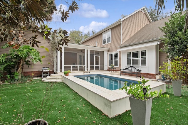 rear view of house with a lawn, a patio area, and a sunroom