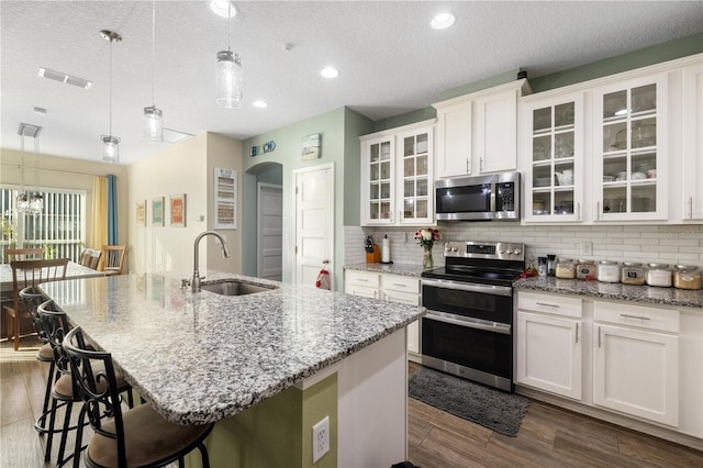 kitchen featuring sink, white cabinets, pendant lighting, and appliances with stainless steel finishes