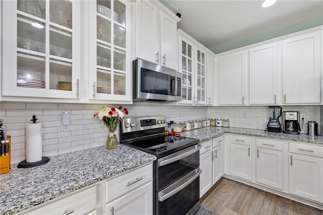 kitchen with white cabinets, backsplash, stainless steel appliances, and a textured ceiling