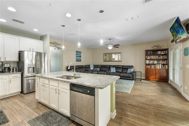 kitchen with a kitchen island with sink, sink, decorative light fixtures, white cabinetry, and stainless steel appliances