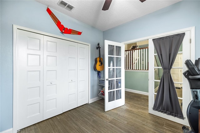 unfurnished bedroom featuring ceiling fan, french doors, dark wood-type flooring, a textured ceiling, and a closet