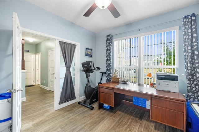 home office with a textured ceiling, light hardwood / wood-style floors, and ceiling fan