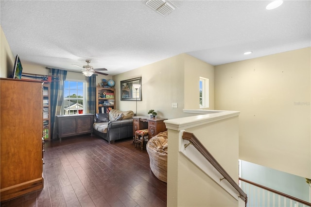 living room with ceiling fan, dark hardwood / wood-style flooring, and a textured ceiling