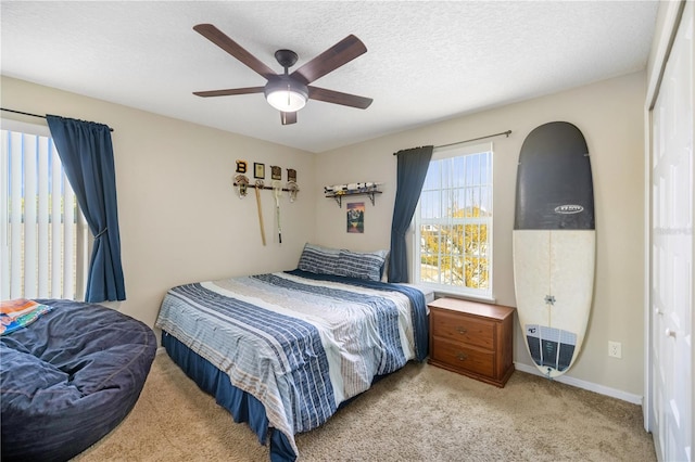 carpeted bedroom with ceiling fan and a textured ceiling