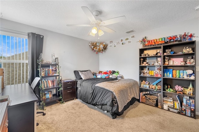 carpeted bedroom featuring ceiling fan and a textured ceiling