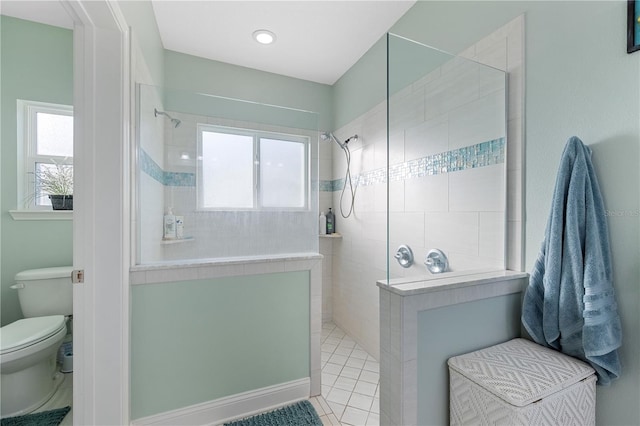 bathroom featuring toilet, a healthy amount of sunlight, and tiled shower