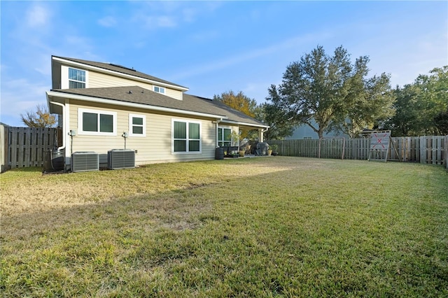 back of house featuring central air condition unit and a yard