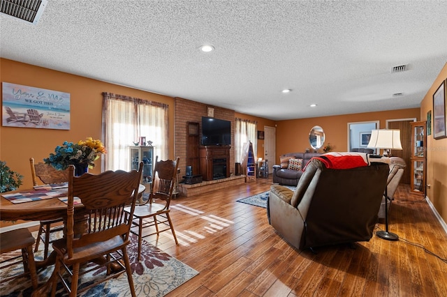 living room with hardwood / wood-style flooring, a textured ceiling, and a fireplace