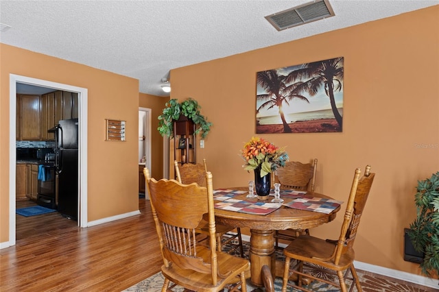 dining space with hardwood / wood-style flooring and a textured ceiling