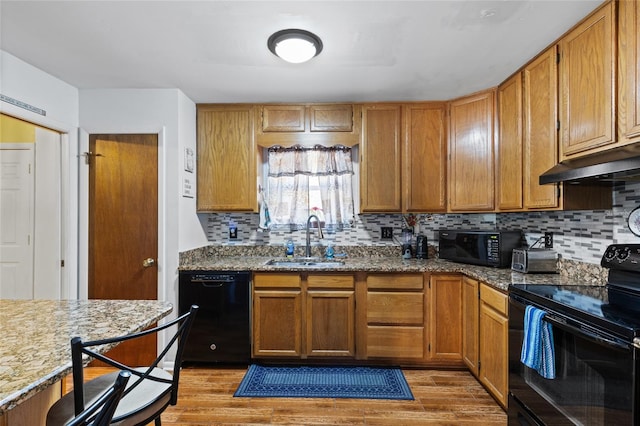 kitchen featuring light stone countertops, sink, hardwood / wood-style floors, and black appliances