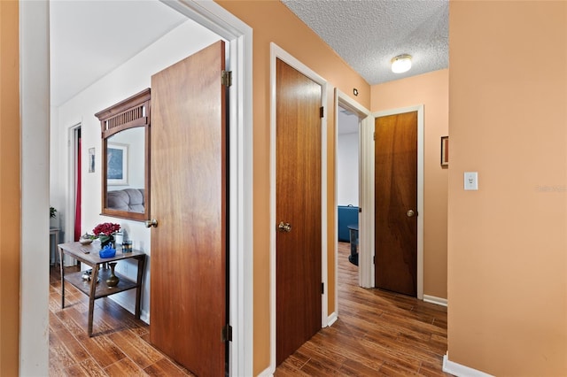 corridor with dark hardwood / wood-style flooring and a textured ceiling