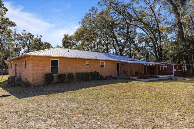 back of property with a yard and a sunroom