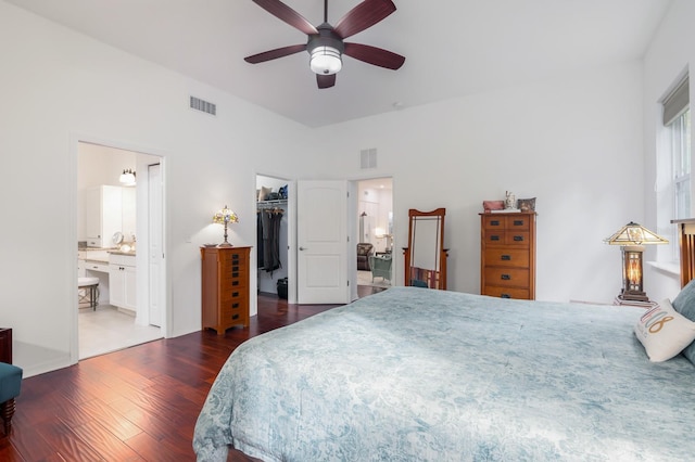 bedroom featuring connected bathroom, ceiling fan, dark hardwood / wood-style flooring, a walk in closet, and a closet