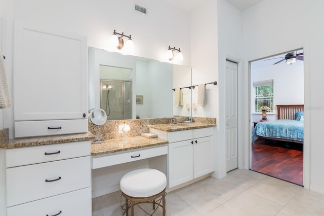 bathroom with tile patterned floors, ceiling fan, a shower with door, and vanity